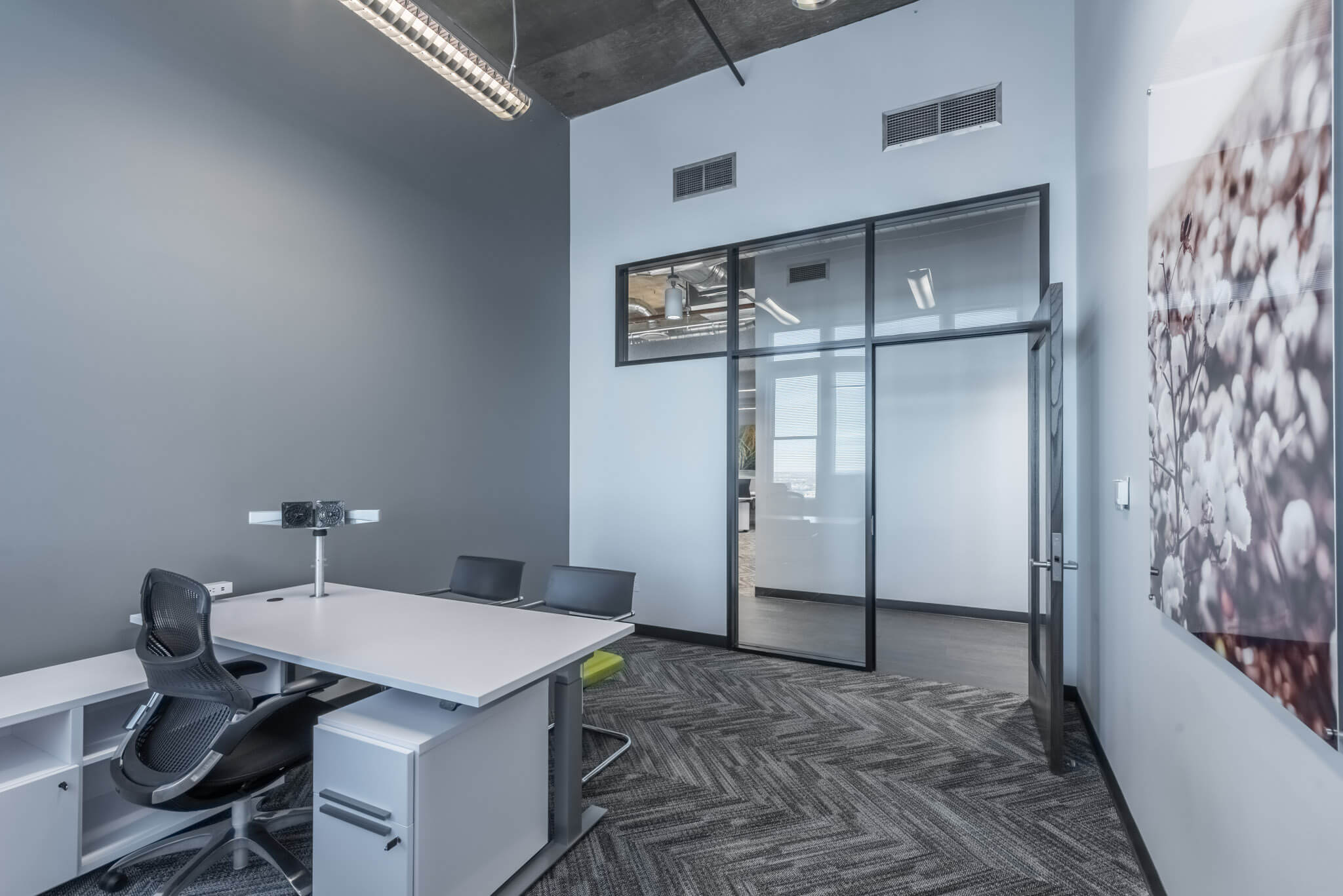 A room with a table and chairs, a desk and a door.