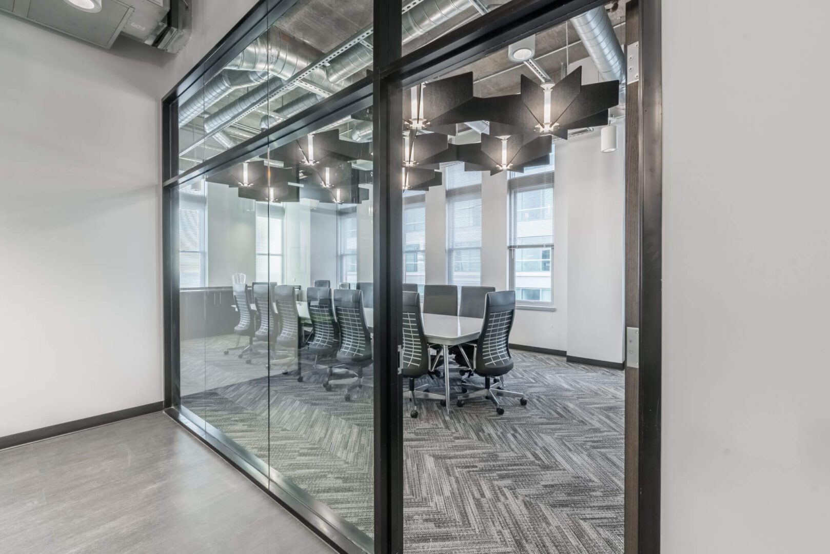 A conference room with glass walls and black chairs.