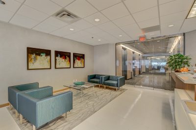 A lobby with blue couches and paintings on the wall.